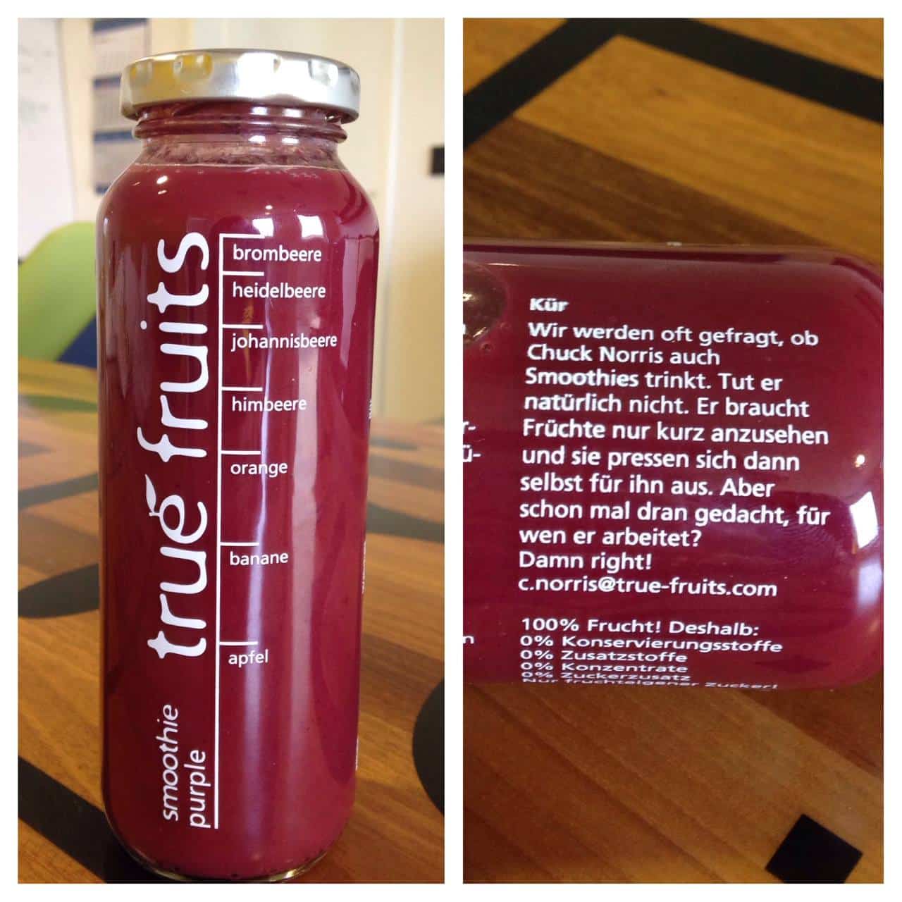 Links: Eine True Fruits Smoothie-Flasche mit rotem Inhalt steht auf einem Holztisch. Die Vorderseite zeigt die Zutatenliste in weißer Schrift, darunter Brombeere, Heidelbeere, Johannisbeere, Himbeere, Orange, Banane und Apfel. Das Logo „true fruits“ ist vertikal entlang der Flasche aufgedruckt. Rechts: Die Rückseite der Flasche mit einem humorvollen Text in weißer Schrift über Chuck Norris. Der Text besagt, dass Chuck Norris keine Smoothies trinkt, weil Früchte sich von selbst auspressen, wenn er sie ansieht, und fragt, für wen er arbeitet, mit der Antwort: „Damn right! c.norris@true-fruits.com“. Darunter steht: „100 % Frucht! Deshalb: 0 % Konservierungsstoffe“.